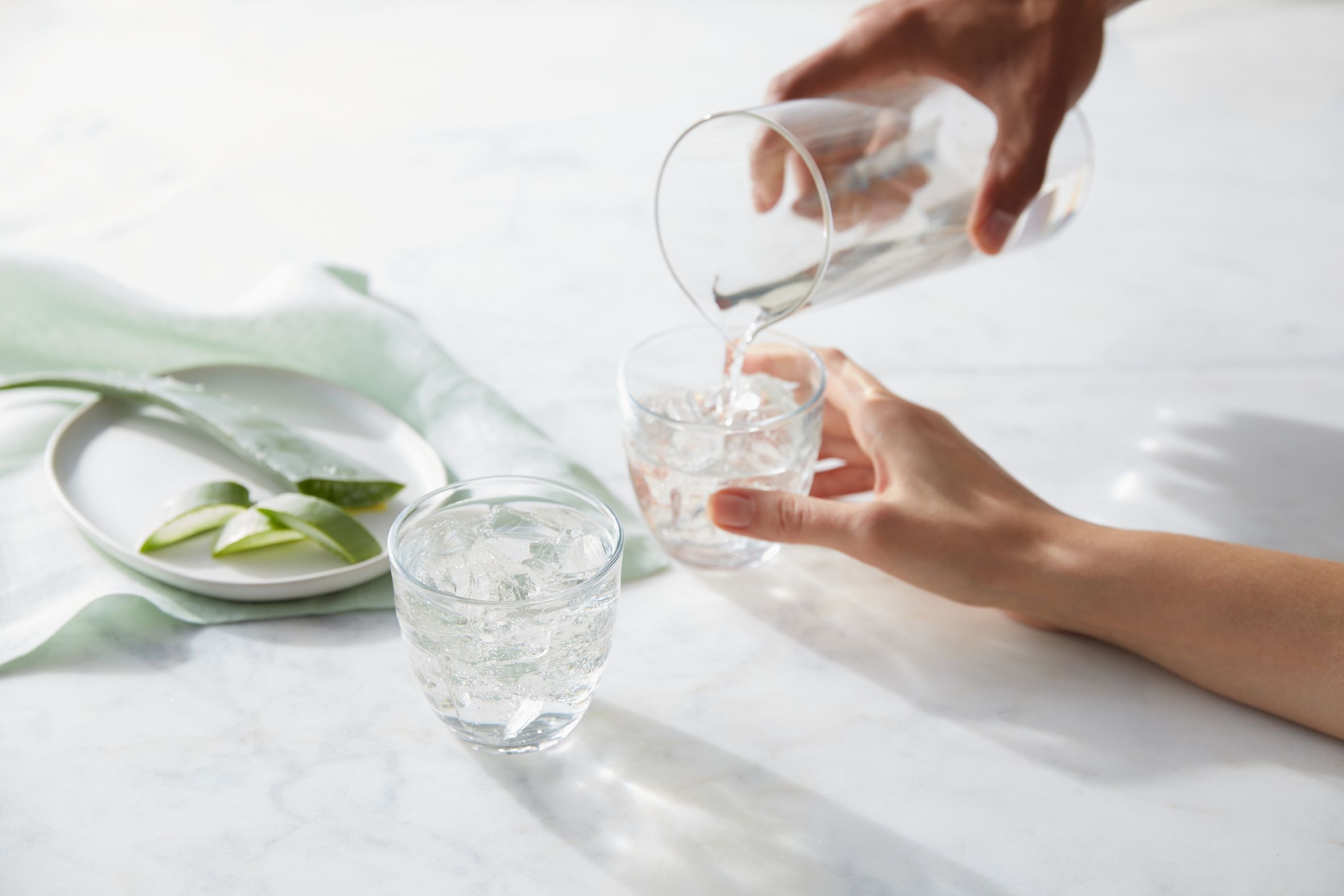 Hand pouring Herbal Aloe Concentrate original flavor into glass