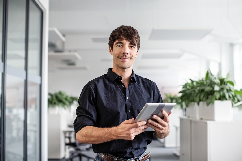 confident businessman holding digital tablet while standing in creative office low res 1